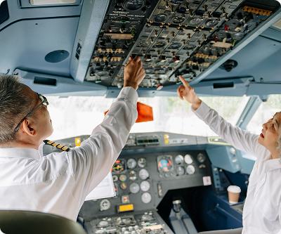 Two pilots operating overhead cockpit switches